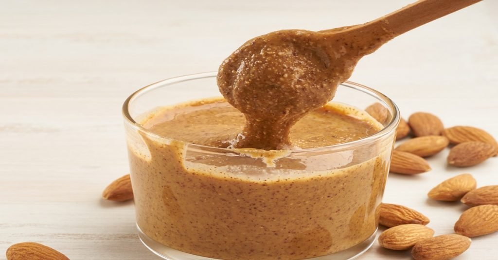 Keto Almond Butter in a pot surrounded by almonds